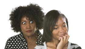 Overprotective mother with teenage daughter reading text messages