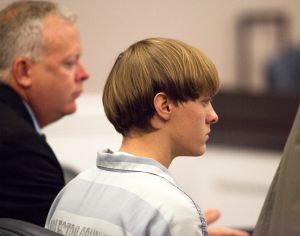 Dylann Roof (R), the 21-year-old man charged with murdering nine worshippers at a historic black church in Charleston last month, is helped to his chair by chief public defender Ashley Pennington during a hearing at the Judicial Center in Charleston