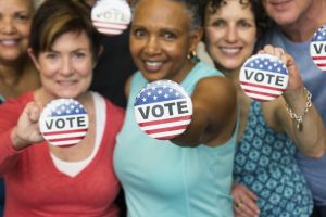 Senior friends holding Vote' buttons