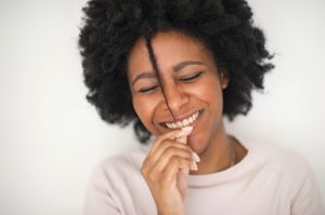 Smiling Black woman playing with hair