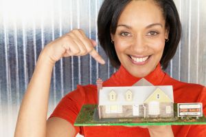 Woman Pointing to Model Home for Sale