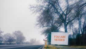 "You are needed" sign in a small town on a foggy morning.