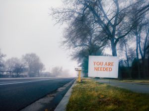 "You are needed" sign in a small town on a foggy morning.
