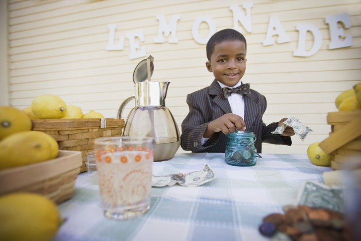 Mixed race boy in suit selling lemonade