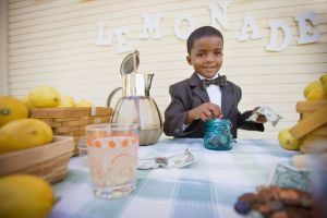Mixed race boy in suit selling lemonade