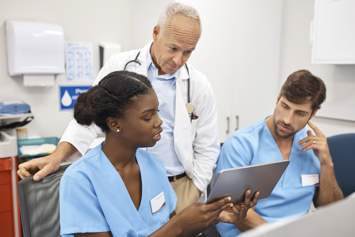 Doctor and nurses discussing over digital tablet