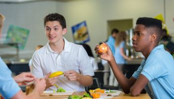 Teenage boys eat lunch in school cafeteria