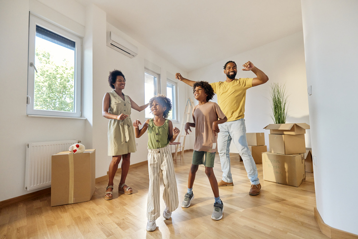 Happy African American family dancing after moving into new home.
