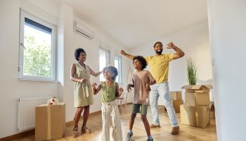 Happy African American family dancing after moving into new home.
