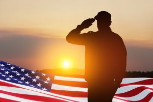 USA army soldier saluting with nation flag. Greeting card for Veterans Day, Memorial Day, Independence Day.