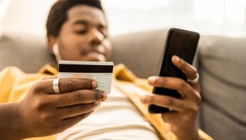 Portrait of young African American man online paying with credit card.