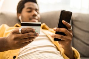 Portrait of young African American man online paying with credit card.