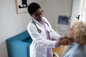 Black female doctor examining patient's throat during an appointment in hospital.