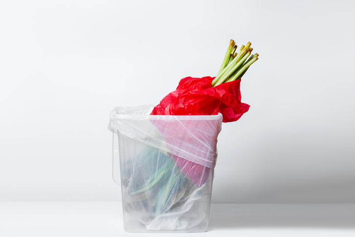 wilted flower. Wilted tulipsin red packaging. In the garbage bucket. Inverted down