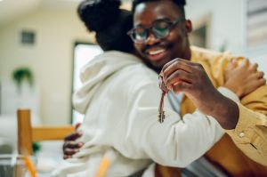 Multiracial sitting in a home office and holing keys of their new home