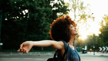 Happy woman with arms outstretched breathing fresh hair