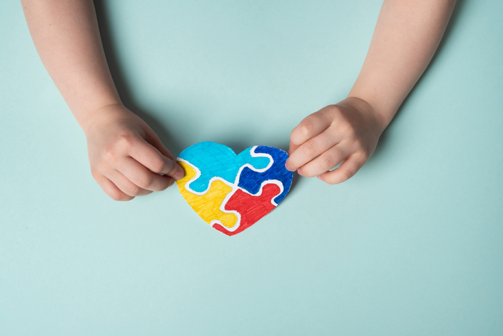 Child hands holding a puzzle heart on a blue background