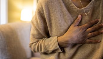 black woman experiences chest pain sitting on sofa