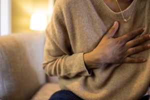 black woman experiences chest pain sitting on sofa