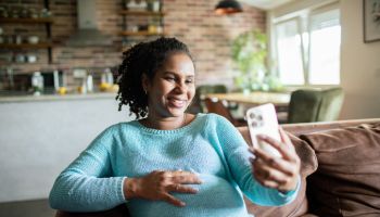 Young pregnant woman using a smart phone at home