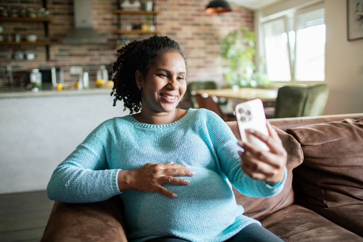 Young pregnant woman using a smart phone at home