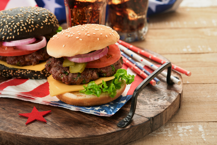4th of July American Independence Day traditional picnic food. American Burger and cocktail, American flags and symbols of USA Patriotic picnic holiday on white wooden background. Top view