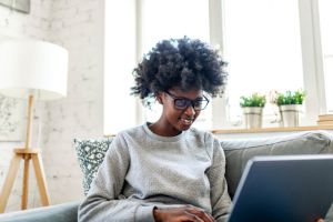 Young adult black woman watching funny movie on laptop