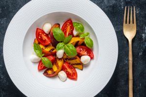 Grilled peach salad with mozzarella, green basil and sauce , close up, top view