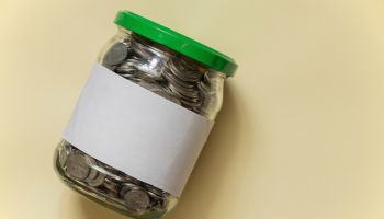 glass jar with Ukrainian pennies on a beige paper background closeup