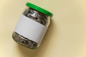 glass jar with Ukrainian pennies on a beige paper background closeup