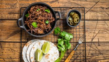 Cooking of mexican pork carnitas taco. Wooden background. Top view