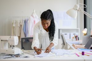 Happy dressmaker designer working in workshop studio