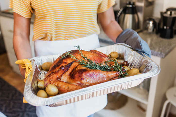 woman cooking and holding turkey meat for Thanksgiving dinner at home in Mexico Latin America, hispanic female preparing food in holidays