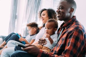 Cheerful family sitting on the sofa and watching TV.