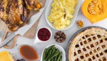 Thanksgiving day dinner table with roasted chicken or turkey, apple pie and other holiday season foods. Traditional autumn fall feast flat lay composition.