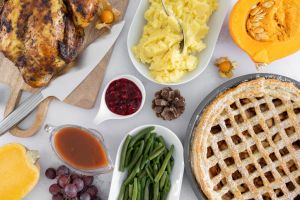 Thanksgiving day dinner table with roasted chicken or turkey, apple pie and other holiday season foods. Traditional autumn fall feast flat lay composition.