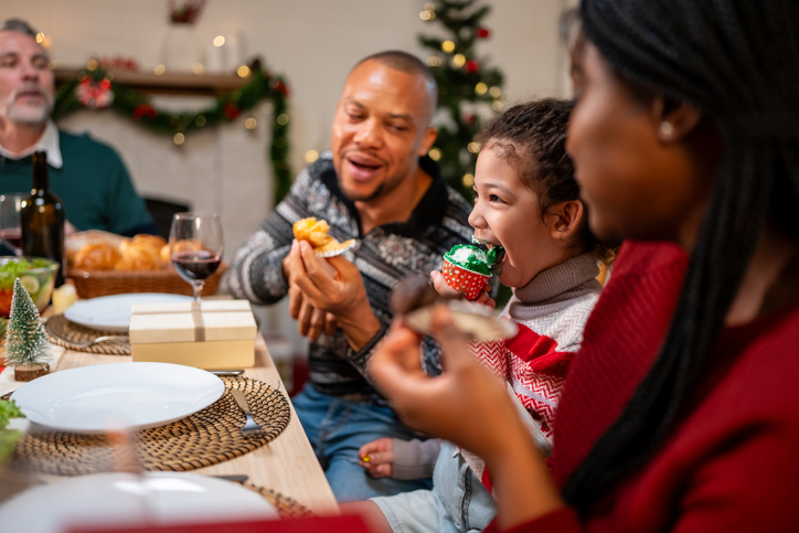 African American family celebrating Christmas party together in house. Attractive group of people having dinner eating foods to celebrate holiday Thanksgiving, X-mas eve on dining table at home.