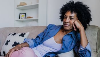Mature woman watching TV in the living room at home