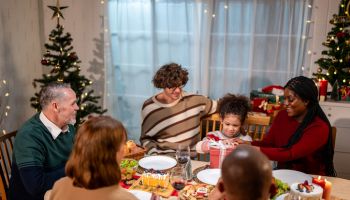 Multi-ethnic family giving gift box to daughter during Christmas party. Attractive little girl receive present from relative while having dinner celebrate holiday Thanksgiving on dining table in house