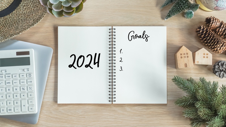 2024 goals new year resolutions on blank note book memo reminder wish list of yearly planner, action plan for work-life balance, good financial health, happy home family, travel aims on office desk