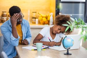 The angry father and a daughter doing homework at the desk.