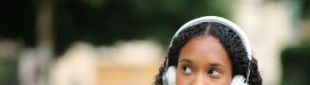 Pensive black woman listening audio in the street