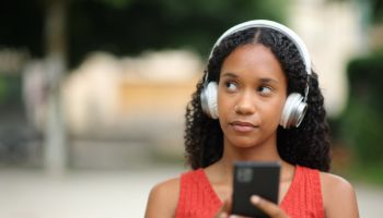 Pensive black woman listening audio in the street