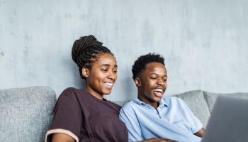 Young adult black couple watching comedy movie on laptop at home