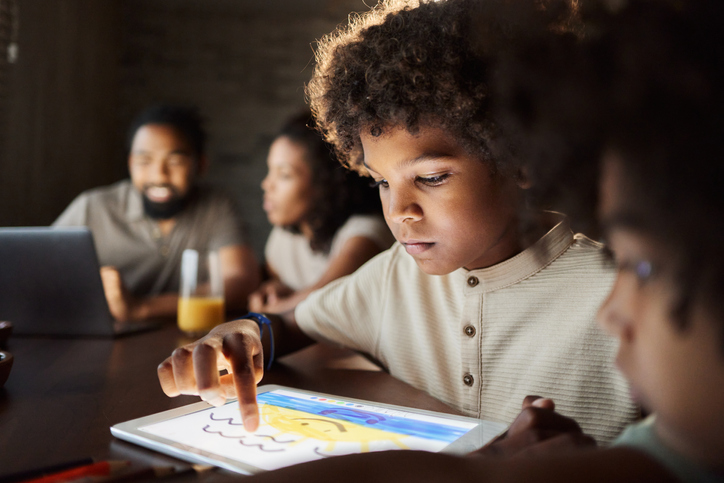 Little black boy using digital tablet at home.