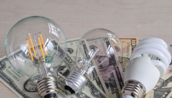 Three types of light bulbs on top of american dollars paper money