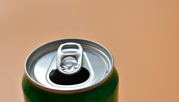 aluminum green drink cans on orange background, open cold fresh beverage