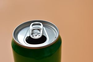 aluminum green drink cans on orange background, open cold fresh beverage