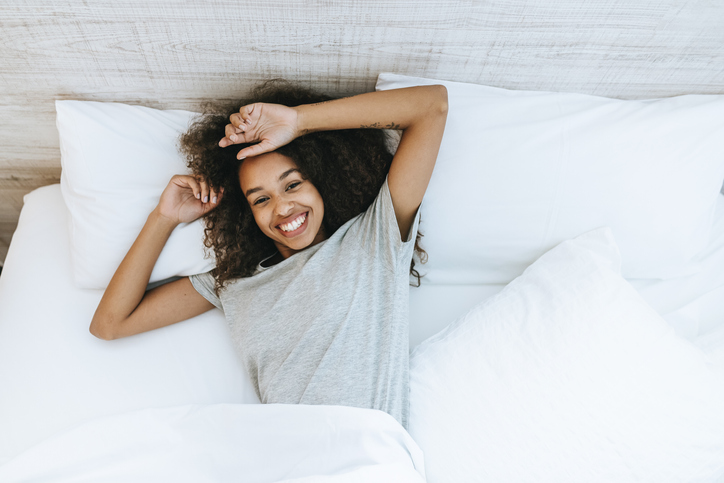 Portrait of woman lying on bed looking at camera