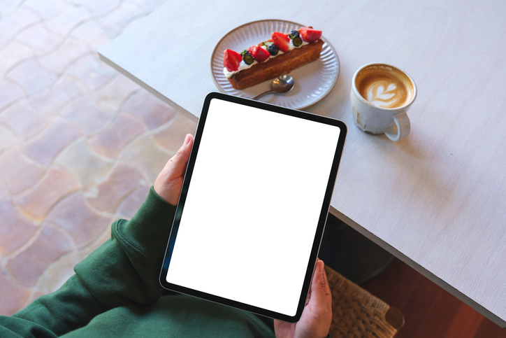 Top view mockup image of a woman holding digital tablet with blank white desktop screen in cafe